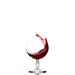 Splash of red wine in a clear glass on a white background