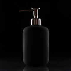Black liquid soap bottle on a black background