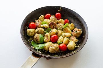 Gnocchi and chicken meatballs with pesto sauce, basil, tomatoes and nuts