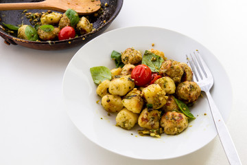 Gnocchi and chicken meatballs with pesto sauce, basil, tomatoes and nuts