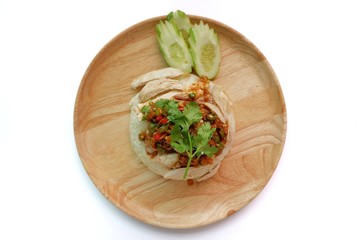 Top eye view closeups of Hainanese chicken rice with soy ginger chili sauce on top or rice steamed with chicken soup and slide cucumber in the soft wooden plate isolated on a white table background.