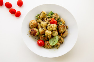 Gnocchi and chicken meatballs with pesto sauce, basil, tomatoes and nuts