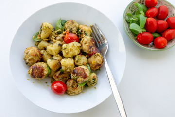 Gnocchi and chicken meatballs with pesto sauce, basil, tomatoes and nuts