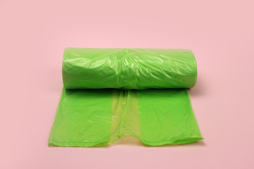 roll of plastic green garbage bags on pink background