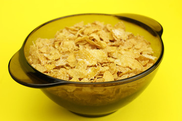 Cornflakes in a glass plate on a yellow background