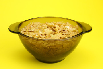 Cornflakes in a glass plate on a yellow background