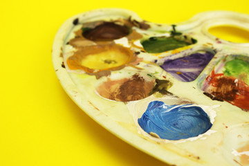 Palette with colors on a yellow background, the artist 's workplace