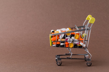 Pills and shopping cart on a yellow background Concept of buying drugs, prices for treatment. Sale in the pharmacy.