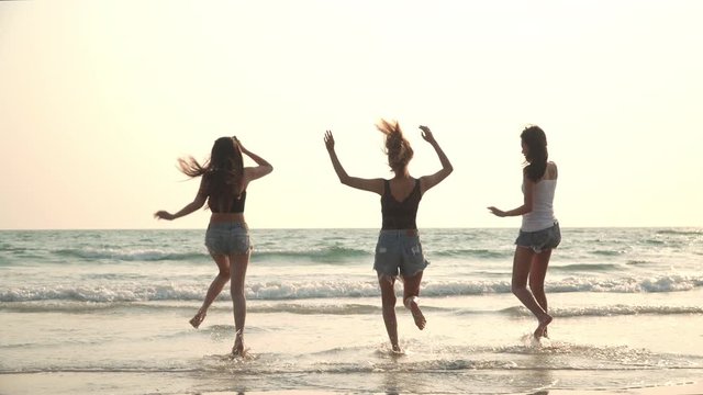 4K Group of Happy young beautiful Asian women friends running on the beach with laughing and smiling together at sunset. Playful attractive woman friendship having fun and relaxing in summer vacation