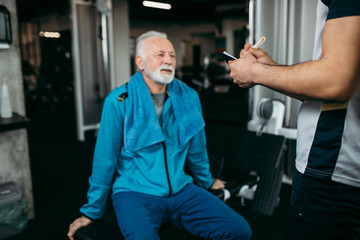 Fototapeta na wymiar Senior man exercising in gym with his personal trainer.