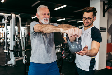 Fototapeta Senior man exercising in gym with his personal trainer. obraz