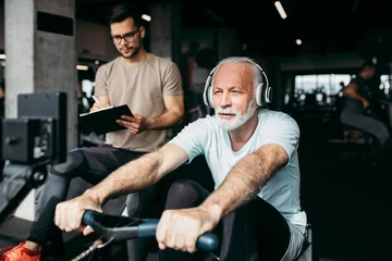 Gordijnen Senior man exercising in gym with his personal trainer. © hedgehog94