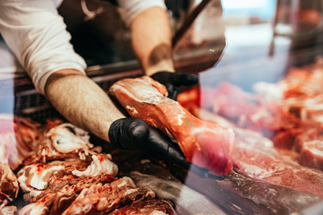 Close up on butcher's hands in gloves working in butchery.
