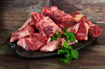 Raw meat with bone on clay plate and brown stone background.Raw meat with beef bone. Beef bone...
