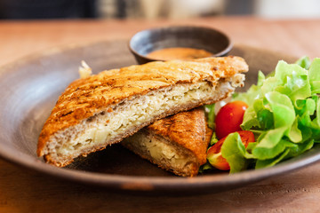 Close-up Grill Cheese Wheat Sandwich Served with Thousand Island Sauce and Salad including Green Oak and Tomato on a Ceramic Plate. Home grilled cheese sandwich for breakfast.
