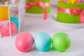 Fototapeta na wymiar Colorful eggs for Easter day, gift box and small cake on the background.