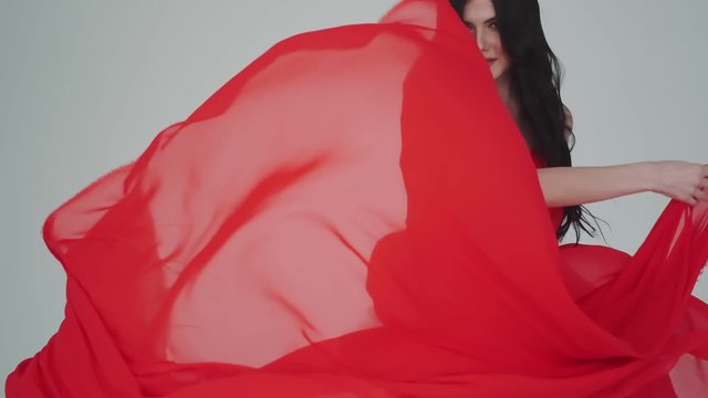 Closeup portrait of a passionate woman in fluttering red dress. girl with a cloth in her hands. fashionable image for advertising perfumes or other concepts.