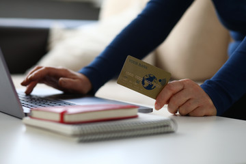 Close-up of woman making payment via internet on laptop. Female holding plastic credit card. Notebook on desktop. Online shopping and modern technology concept