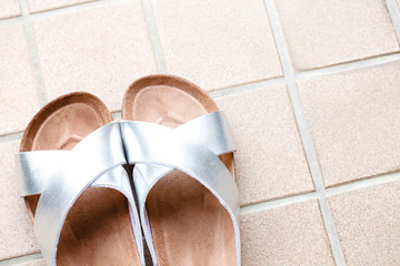 タイルの上にシルバーと茶色のスリッパを斜めに撮る