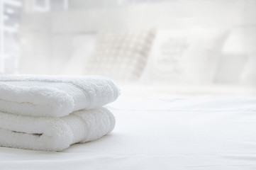 White folded towels on white bed, copy space.