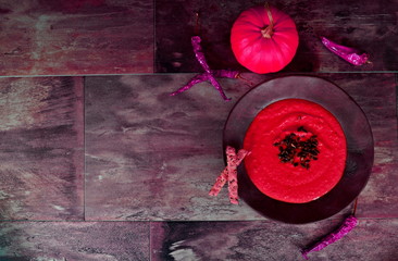 Creamy pumpkin soup topped with pumpkin seeds with green pea leaves, Dark brown stone background