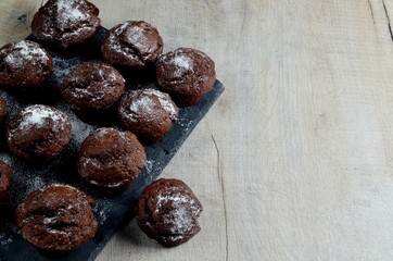 chocolate muffins on black stone plate and gray wood background, place for text