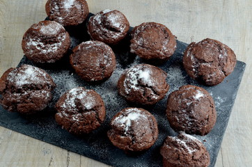 chocolate muffins on black stone plate and gray wood background, place for text