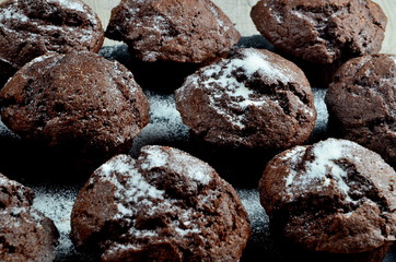 chocolate muffins on black stone plate and gray wood background, place for text