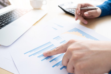 Businessman is inspecting and pointing at the business reports graphs to audit the financial reports. Analyzing the revenue and auditing the budget concept.