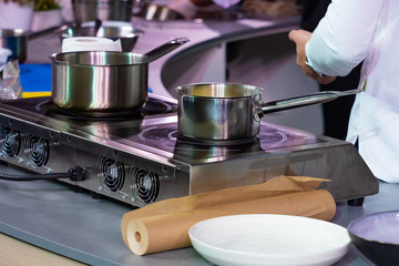 Metal ladles on the stove in the restaurant. Culinary concept. The preparation of sauces. Utensils and equipment for the cafe. Restaurant kitchen. The chefs prepare the soups. Stainless steel cookware