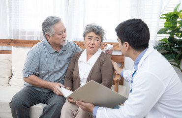 Fototapeta premium Young caucasian doctor man talking result of examination on tablet to senior elderly old retirement asian woman with old man take care her beside.healthcare and medical concept.