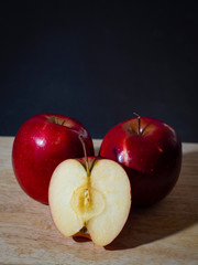 Vertical photo of two red and half apples on wood