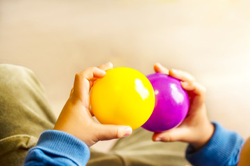Fototapeta na wymiar 紫と黄色のボールを持つ子供の手