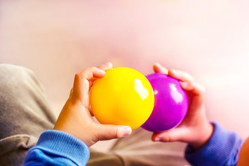 Fototapeta na wymiar 紫と黄色のボールを持つ子供の手