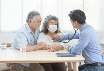 Fototapeta premium Young caucasian doctor man talking result of examination on file folder to senior elderly old retirement asian woman with old man take care her beside.healthcare and medical concept.