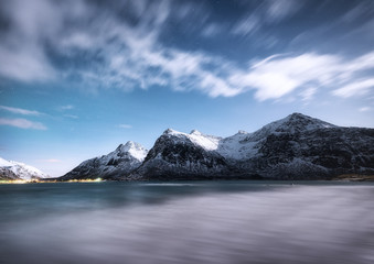 Obraz premium Mountains and reflections on water at night. Winter landscape. The sky with stars and clouds in motion. Nature as a background. Norway - travel
