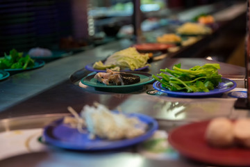 Japan restaurant food conveyor or belt buffet. belt sushi in japan restaurant with blurred background.