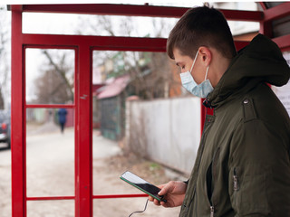 guy in a medical mask stands at a bus stop. isolated to avoid viral disease covid-19 measles flu...