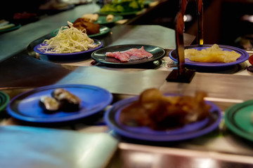 Japan restaurant food conveyor or belt buffet. belt sushi in japan restaurant with blurred background.