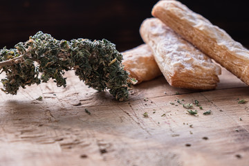 three cookies with marijuana lie on a wooden board. Near big bud cannabis. Horizontal