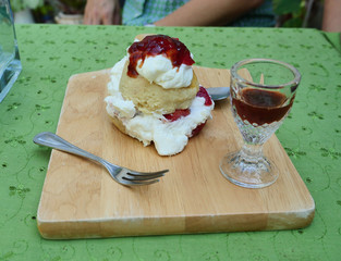 Scones with strawberry jam and clotted cream on green table, Biscuit with spoon and fork on a wooden tray