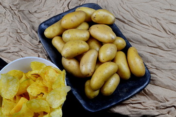 Small washed potatoes and potato chips on a fabric background. View from above. Raw potato food