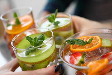 Close-up view of glasses with colourful cocktails and slices of fruits. Yummy drinks on fun party. Orange kiwi strawberry in cooling beverages. Celebration concept