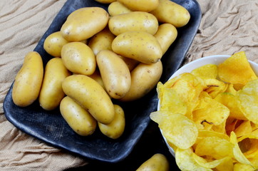 Small washed potatoes and potato chips on a fabric background. View from above. Raw potato food
