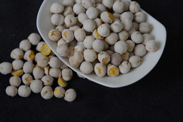 White roasted chickpeas in a bowl and poured in front of it.