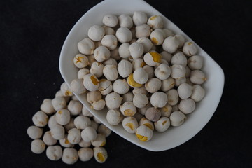 White roasted chickpeas in a bowl and poured in front of it.