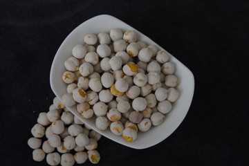Fototapeta na wymiar White roasted chickpeas in a bowl and poured in front of it.