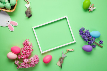 Naklejka na ściany i meble Easter background with hyacinth flowers, colored eggs and decorations on color background with frame. Top view. Flat lay