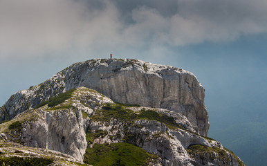Hiker man standing on a cliff in Retezat National park in Carpathian mountain range, Romania