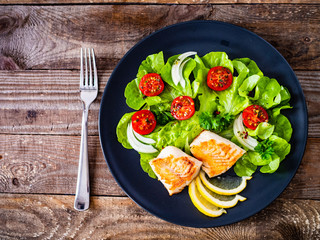 Fish dish - fried cod fillet with vegetables on wooden table